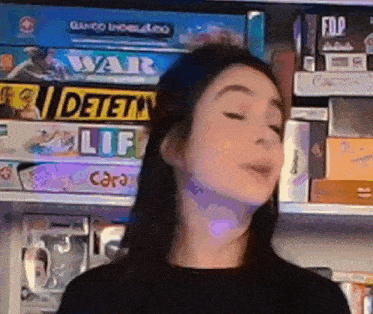 a woman is standing in front of a shelf filled with lots of board games .