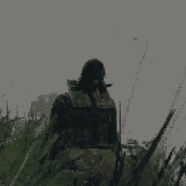 a man in a military uniform is sitting in the grass with a gun