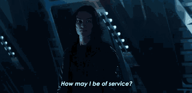 a woman is standing in a dark room and asking how may i be of service
