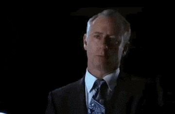 a man in a suit and tie is saying `` now go . be brilliant '' in a dark room .