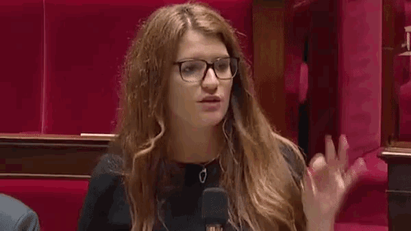 a woman wearing glasses and headphones is talking into a microphone in a theatre .