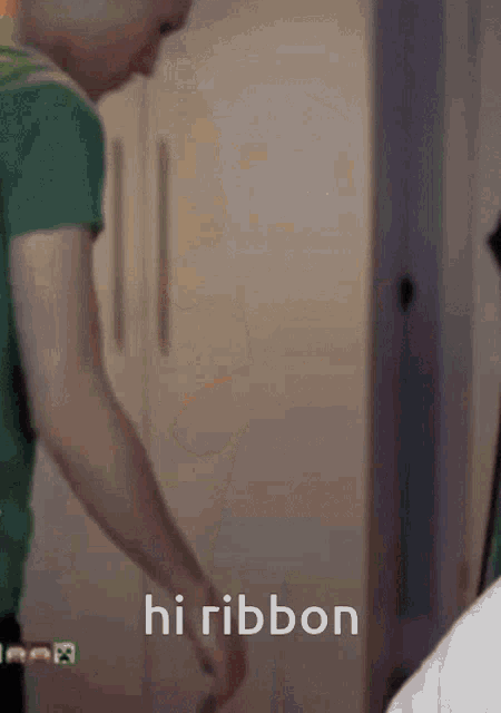 a man in a green shirt is standing in front of a white door with the words hi ribbon on the bottom