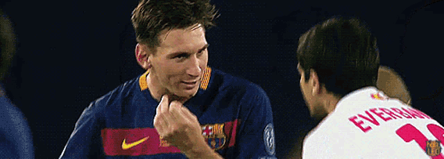 two soccer players are talking to each other on a field .