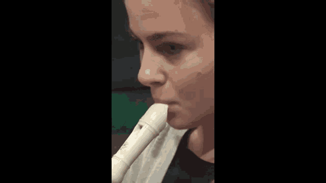 a close up of a woman playing a recorder with her mouth open .