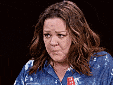 a woman in a blue tie dye shirt making a funny face