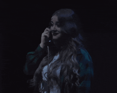 a woman in a plaid jacket is talking on a telephone