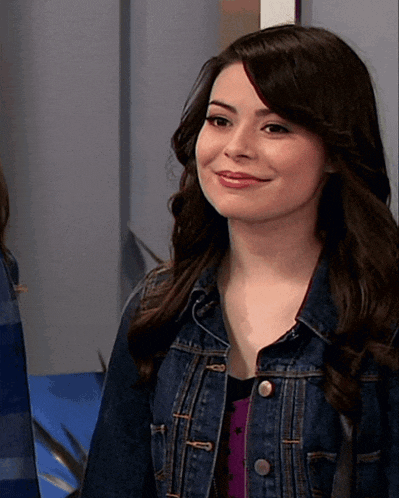 a woman wearing a denim jacket is smiling and looking at the camera
