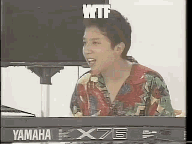 a man is sitting at a yamaha kx76 keyboard .