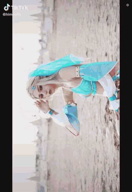 a woman in a blue and white costume is laying on a beach with a tiktok watermark