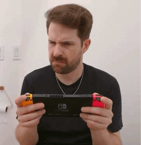 a man is holding a nintendo switch and making a face