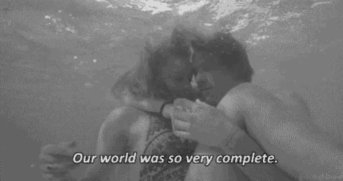 a man and a woman are kissing underwater in a pool .