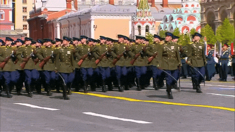 a group of soldiers march down a street in front of buildings