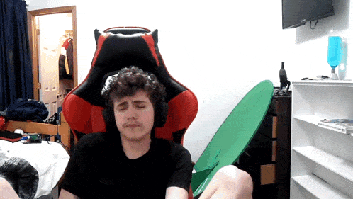 a man wearing headphones sits in a red and black gaming chair