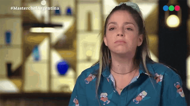 a woman wearing a blue shirt with simpson faces on it is on a tv show called masterchef argentina