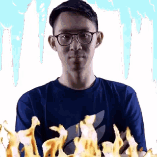 a man wearing glasses and a blue shirt is holding a bunch of flames