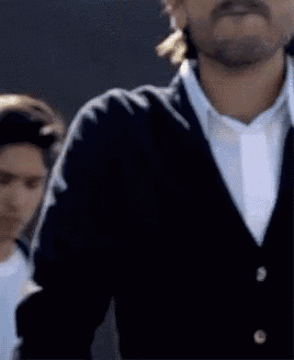 a man with a beard wearing a black cardigan and white shirt