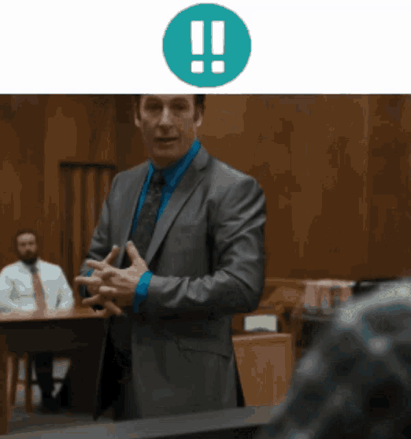 a man in a suit and tie is giving a speech in a courtroom with an exclamation point above him