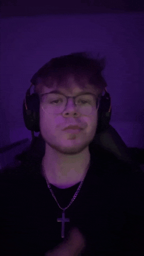 a young man wearing glasses and headphones looks at the camera