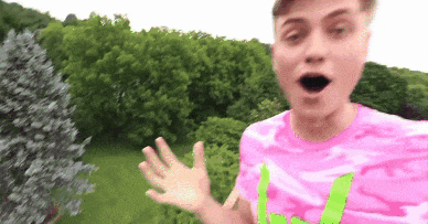 a young man wearing a pink shirt with a green letter l on it