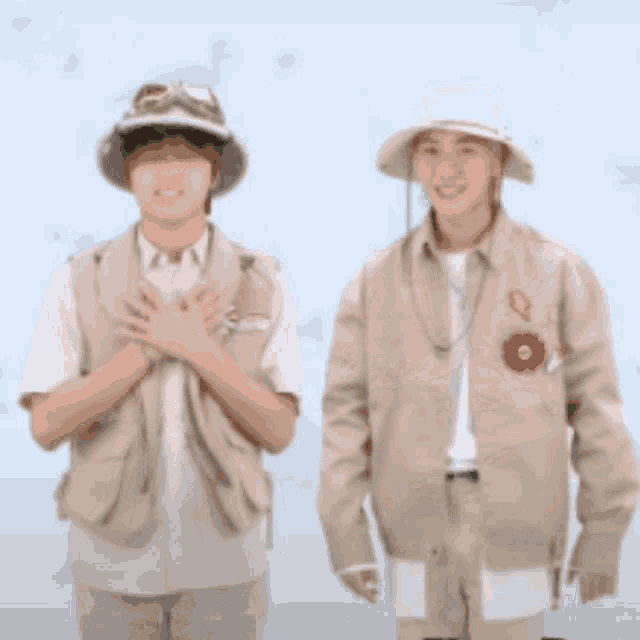 two young men wearing hats and vests stand next to each other