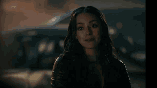 a woman in a leather jacket is standing in front of a car