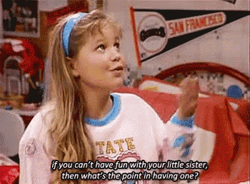 a little girl is sitting on a bed wearing a shirt that says tate .