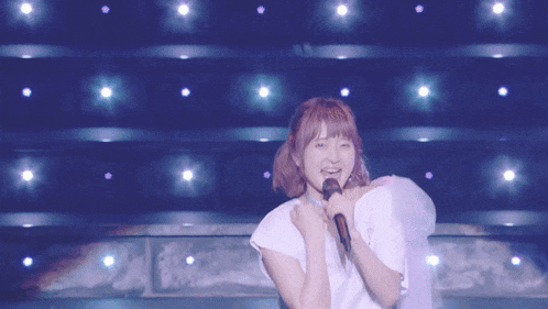 a woman is singing into a microphone in front of a blue background