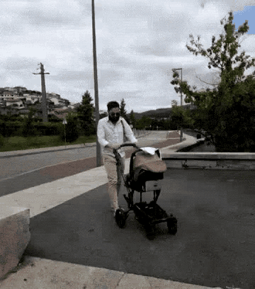 a man wearing sunglasses pushes a stroller down the street