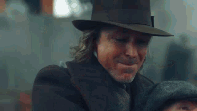 a man in a hat and tie is holding a knife