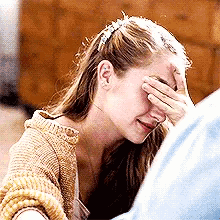 a woman is covering her face with her hand while crying .