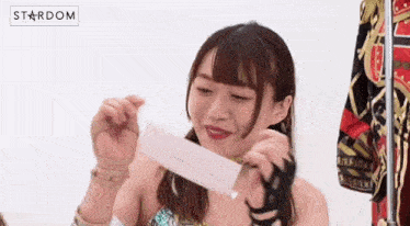 a young woman is holding a piece of paper in her hands .
