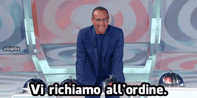 a man in a suit is standing in front of a sign that says vi richiamo all 'ordine