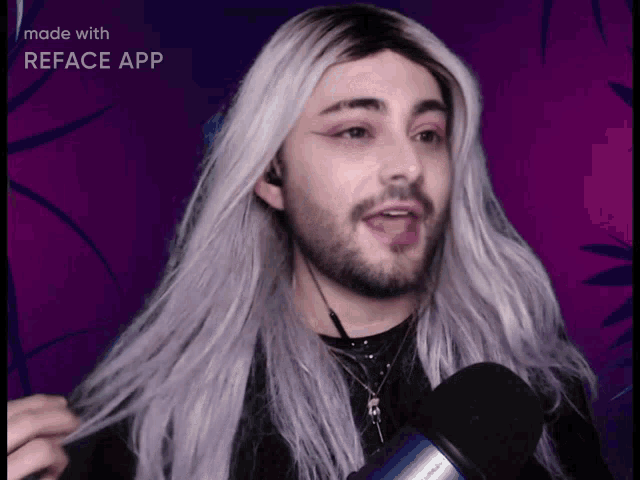 a man with long gray hair and a beard is talking into a blue microphone