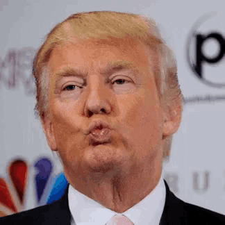 donald trump is blowing a kiss while wearing a suit and tie .