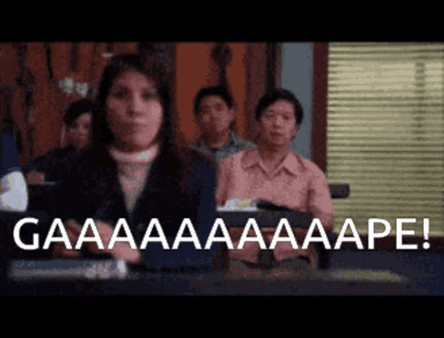 a woman is sitting in front of a group of people with the words gaaaaaaaape written on the screen