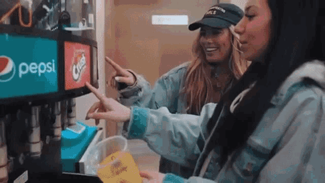 two women are getting a drink from a pepsi machine