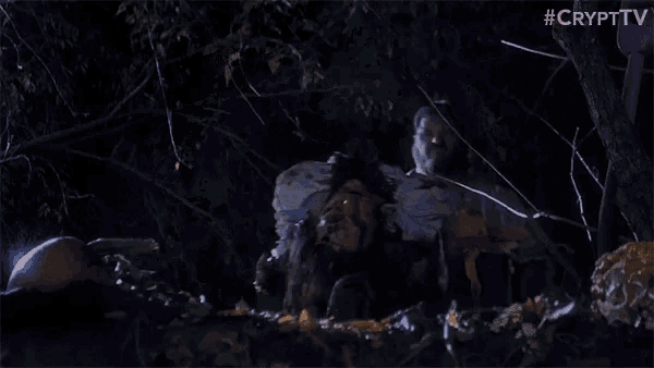 a t-rex is being attacked by a group of people in a dark forest at night .