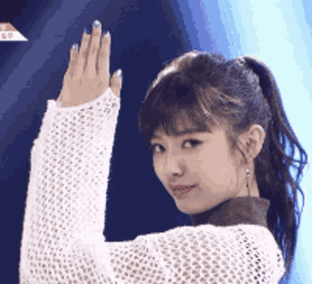a woman in a white sweater is waving her hand in the air .