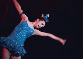 a woman in a blue dress is dancing with a microphone on her head