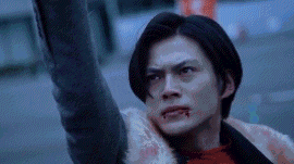 a man with blood on his face is holding his arm up in the air in a blurry photo .