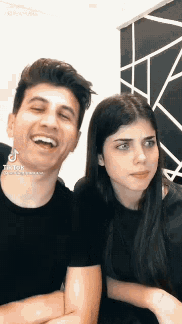 a man and a woman are sitting next to each other and laughing together .