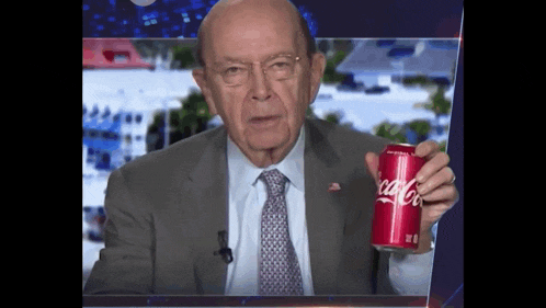 a man in a suit and tie is holding a red can of coca-cola