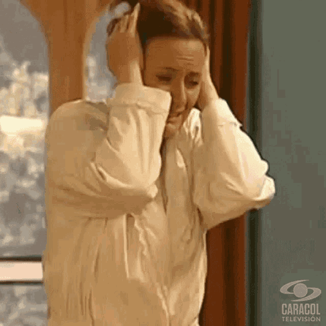 a woman in a white robe is covering her ears with her hands .