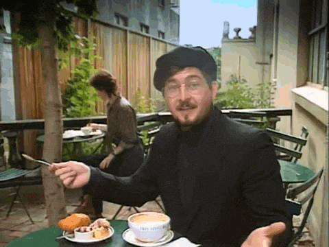 a man sitting at a table with a cup of cappuccino and a spoon in his hand
