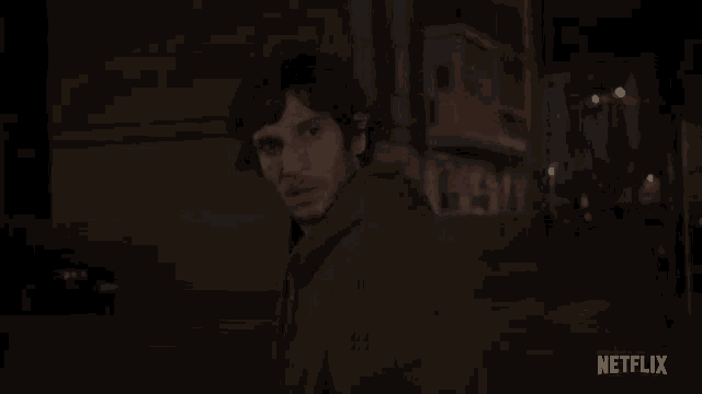 a man in a green jacket is walking down a street at night with a netflix logo in the corner .