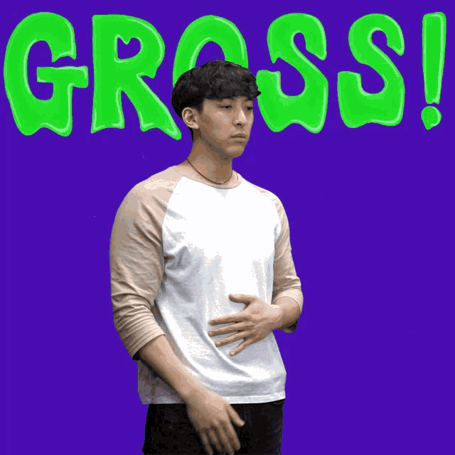 a young man holds his stomach in front of a green gross sign