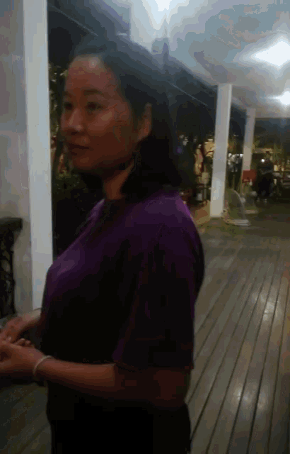 a woman in a purple shirt stands in front of a white pillar