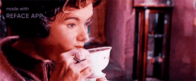 a woman is drinking a cup of tea while wearing a ring on her finger .