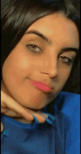 a close up of a woman 's face with a blue shirt on and a pink lip .