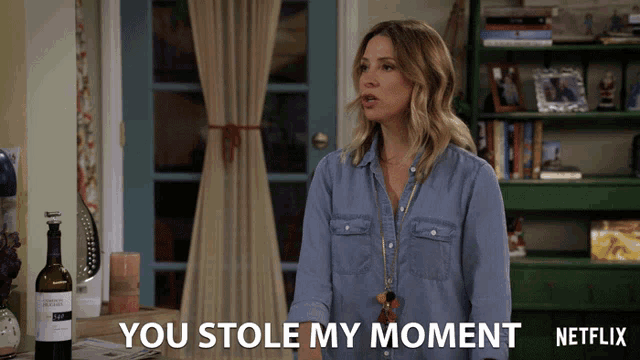 a woman is standing in front of a bottle of wine and says you stole my moment